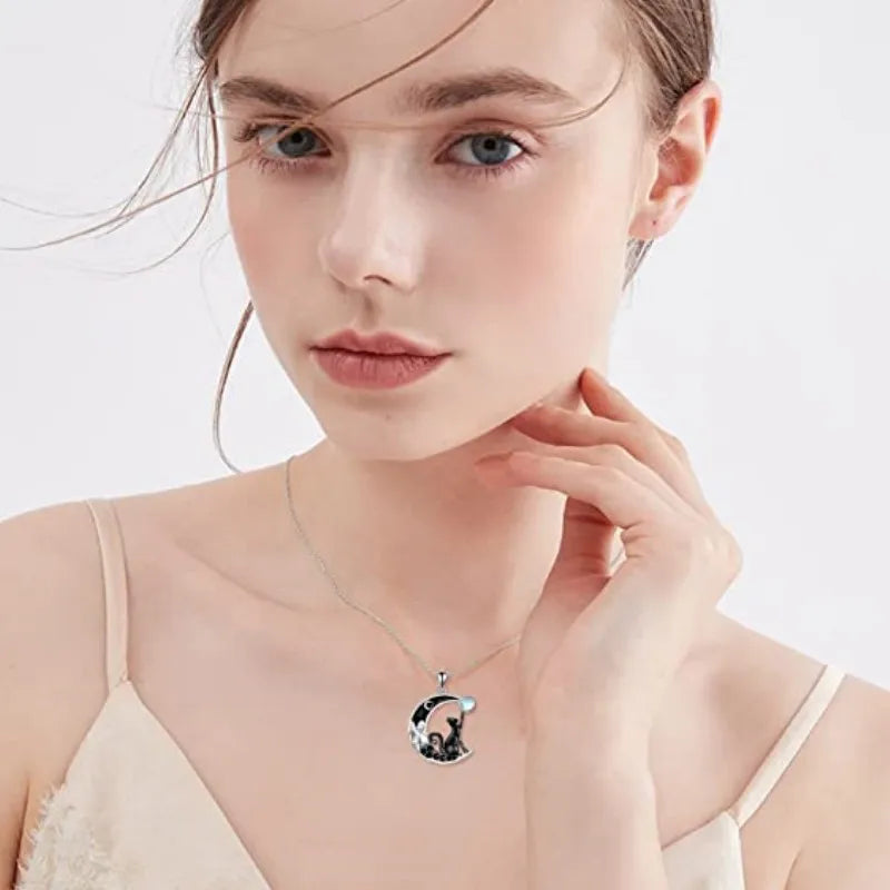 Fair-skinned woman in a cream camisole wears KittyNook Cat Co.'s Cute Black Kitty Moon Necklace, looking at the camera.