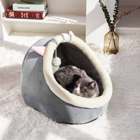 Thumbnail for A gray cat relaxes in the KittyNook Cat Co. Cute Comfortable Cat Nest Bed with ears on a fluffy white rug by a vase.