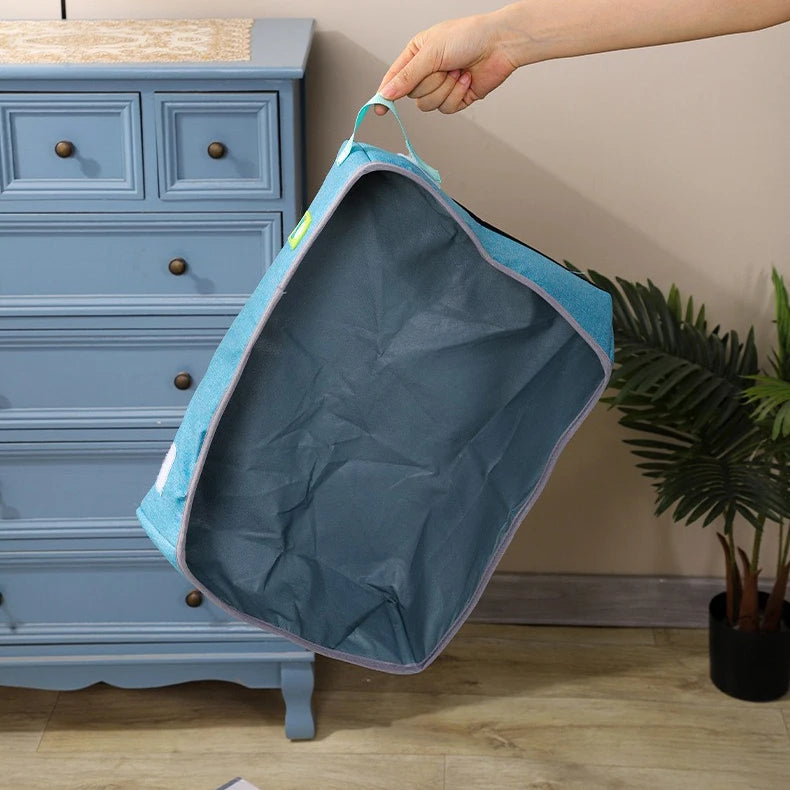 A hand holds the KittyNook Cat Co. Portable Cat Litter Box, a discrete blue mesh travel litter solution, near a dresser.