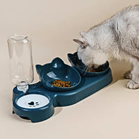 Thumbnail for A gray cat eats from the KittyNook Cat Co. Cute 3 In 1 Cats Bowls With Water Feeder shaped like a cat’s head.