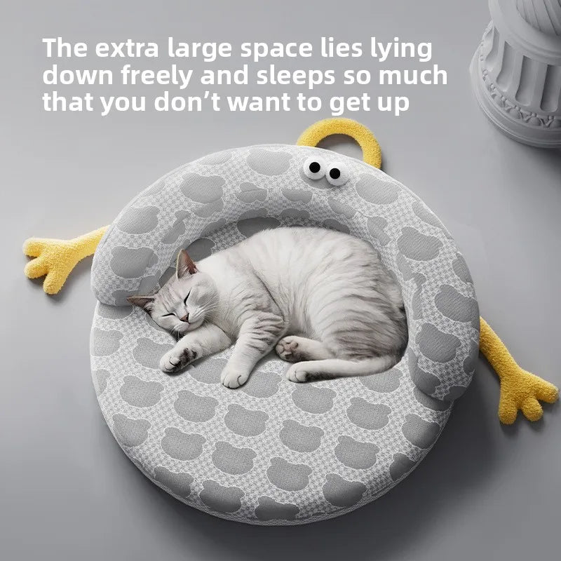 A gray and white cat naps curled on KittyNook Cat Co.'s Ice Silk Cat Nest, a round cartoon-themed summer bed.