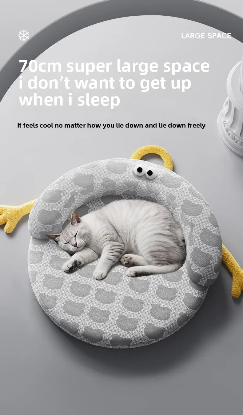A white cat curls up on a gray KittyNook Cat Co. Ice Silk Cat Nest with cartoon eyes and yellow arms.