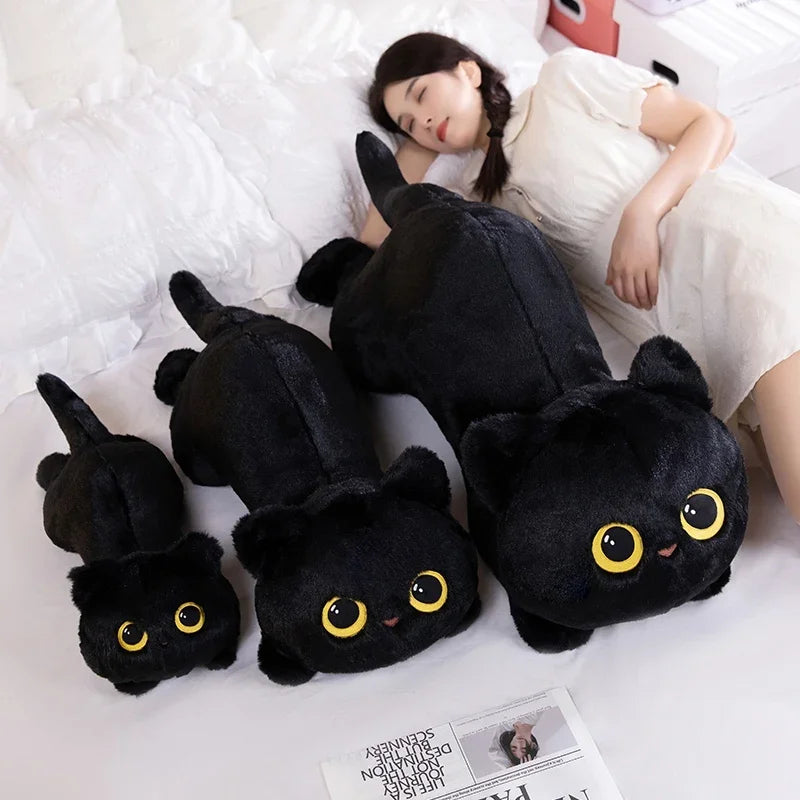 A woman lies on a bed with three KittyNook Cat Co. Plush Cat Pillow: Whimsical Home Cozy—ideal for cat lovers.
