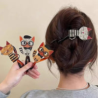 Thumbnail for A person wears The Acrylic Cat Hairpin by KittyNook Cat Co., holding three colorful cat hair accessories.
