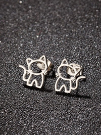 Thumbnail for KittyShine Stainless Steel Ear Studs by KittyNook Cat Co.—cute cat-shaped accessories on a textured black surface.