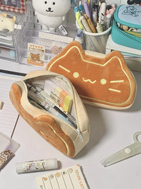 Thumbnail for Two KittyNook Cat Co. Caramel Cat Plush Pencil Cases, one open with stationery, sit on a tidy desk with cute supplies.
