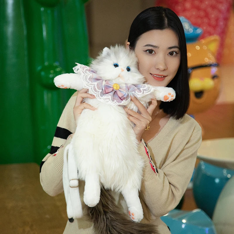 A woman smiles, holding her white cat in The Purrfect Cat Lover’s Bag by KittyNook Cat Co. in a colorful room.