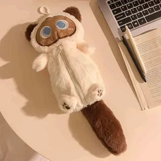 The Kawaii Big-Eyed Cat Plush Pencil Case by KittyNook Cat Co. sits near an open book and pen on a desk.