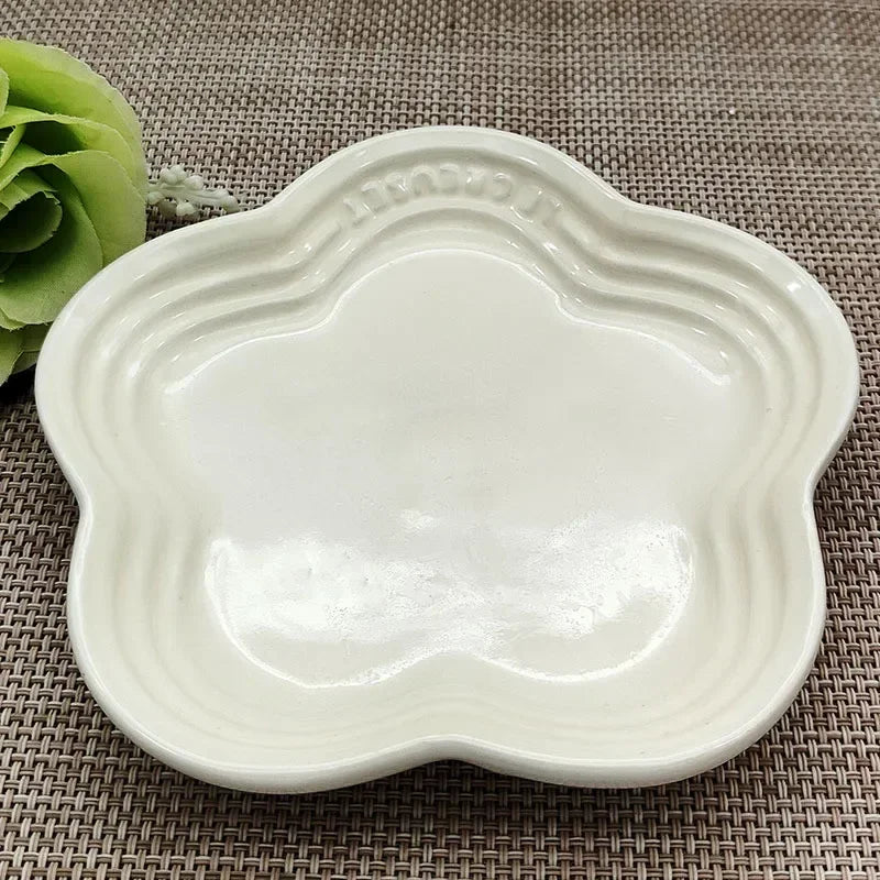 KittyNook Cat Co. Extra Wide Raised Flower Cat Bowl, white and flower-shaped, on a brown woven surface with green decor.