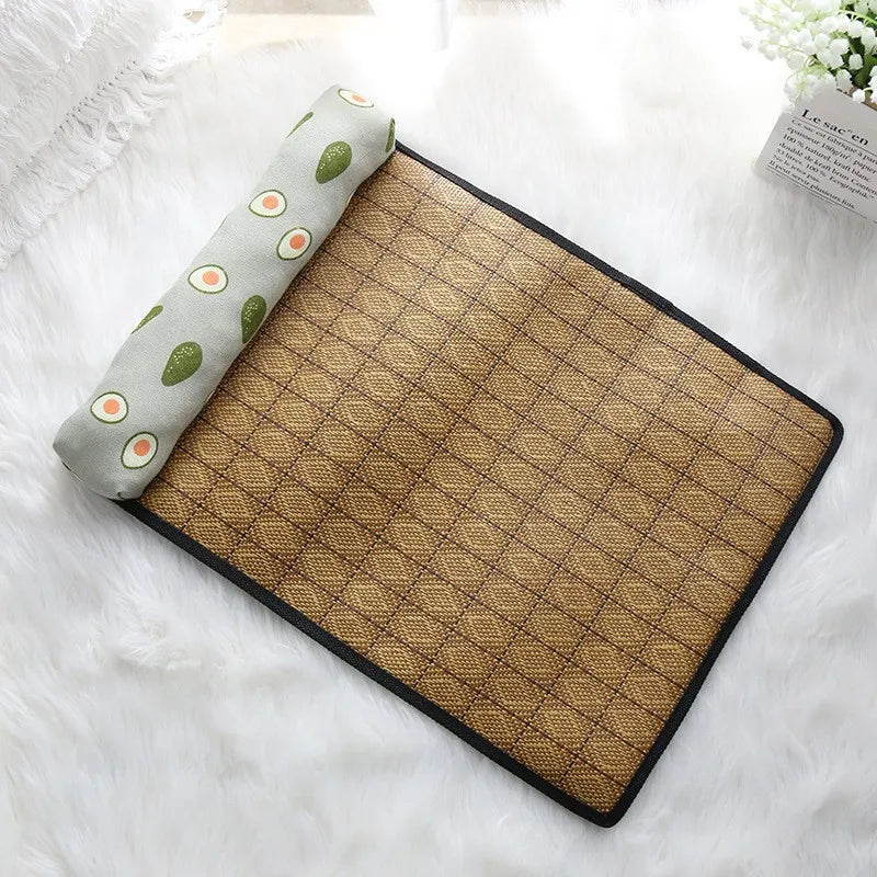 KittyNook Cat Co. Natural Rattan Cat Sleeping Mat with avocado pillow, shown on a white fluffy surface.