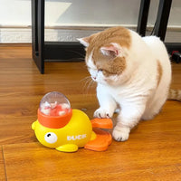 Thumbnail for A cat taps a yellow KittyNook Cat Co. Non-Toxic Pet IQ Food Leak Tumbler on a wooden floor.