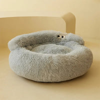 Thumbnail for The KittyNook Cat Co. Warm & Soft Cat Sleeping Pod is a fluffy light gray round bed with cartoon eyes on the edge.