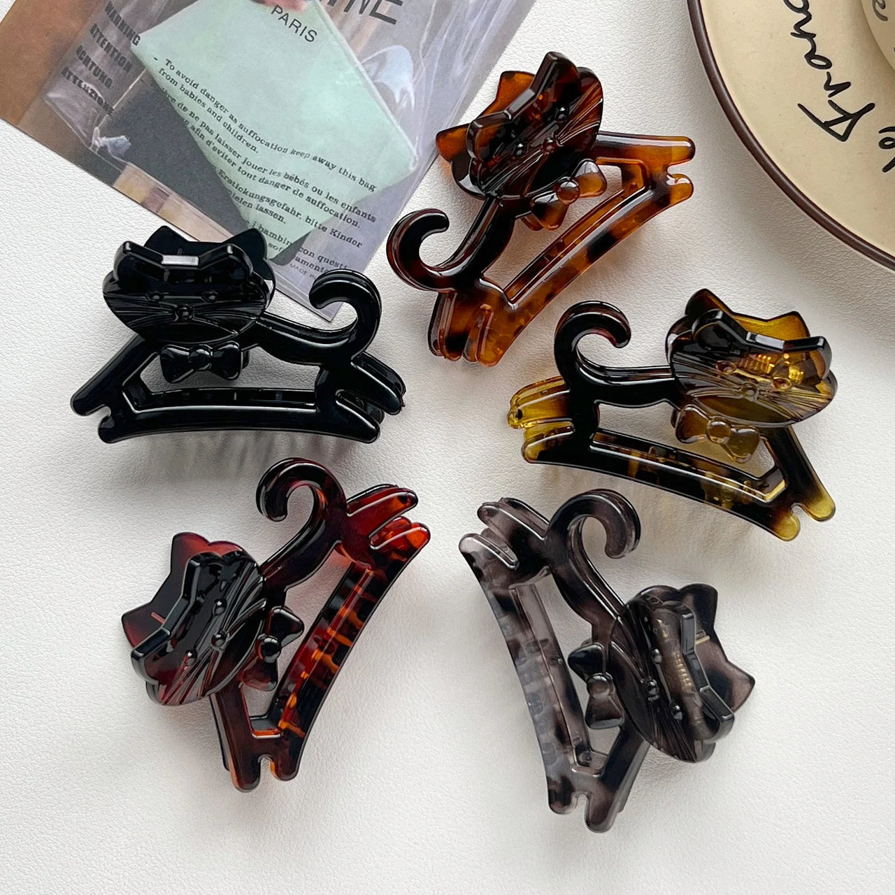 Five KittyNook Cat Co. Cute Cat Hair Claws in assorted colors arranged in a circle on a white surface.