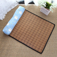 Thumbnail for The Natural Rattan Cat Sleeping Mat by KittyNook Cat Co. features a blue pillow with cloud and sun faces, beside white flowers.