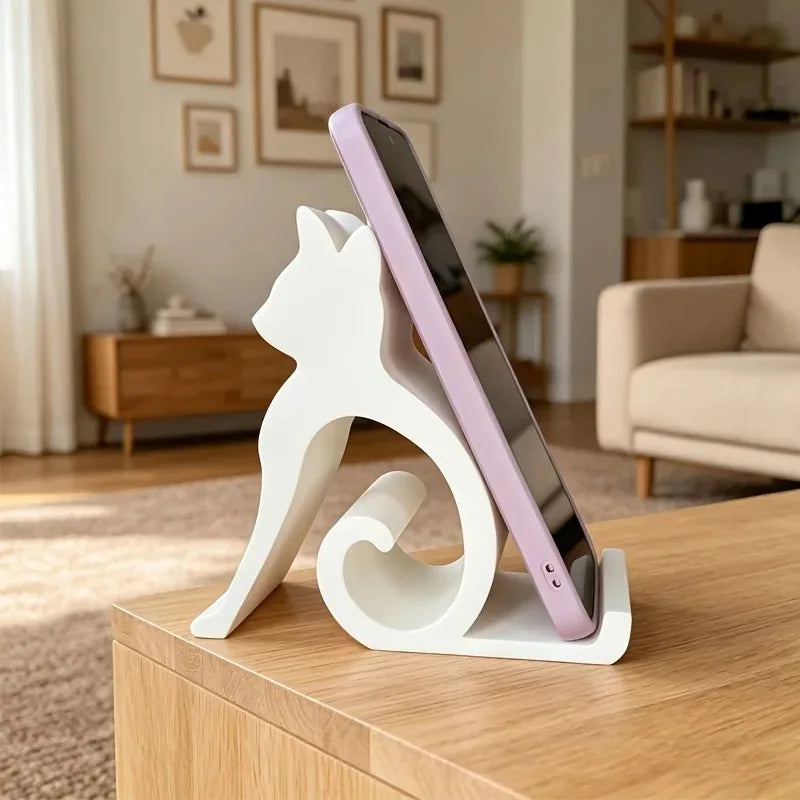 A Cute Cat Phone Stand – Adjustable Mobile & Tablet Holder holds a smartphone on a wooden table.