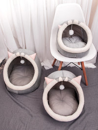 Thumbnail for Three KittyNook Cat Co. Cute Comfortable Cat Nest Beds in gray with pink ears, one on a chair, two on a rug.