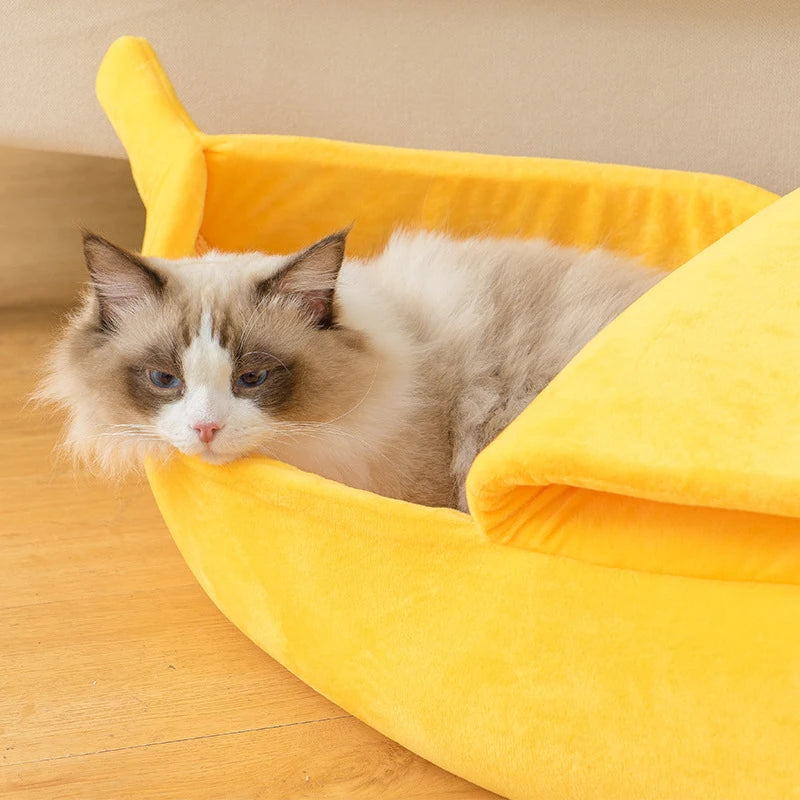 A fluffy cat lounges in the KittyNook Cat Co. Cute Funny Banana Shape Cat Bed with orthopedic support.