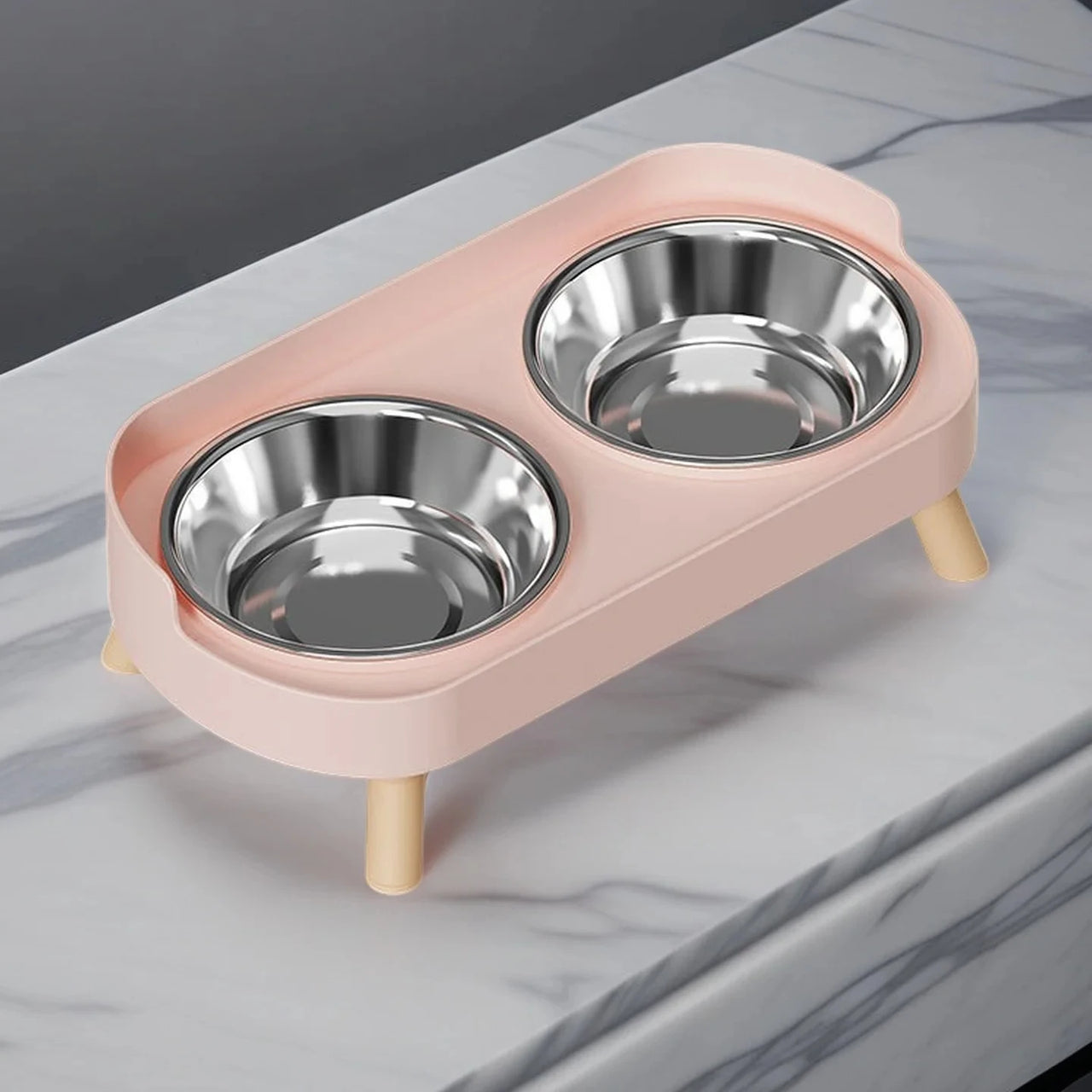 The KittyNook Dopamine DuoLift Cat Feeder in pink with 2 stainless steel bowls on a marble countertop.