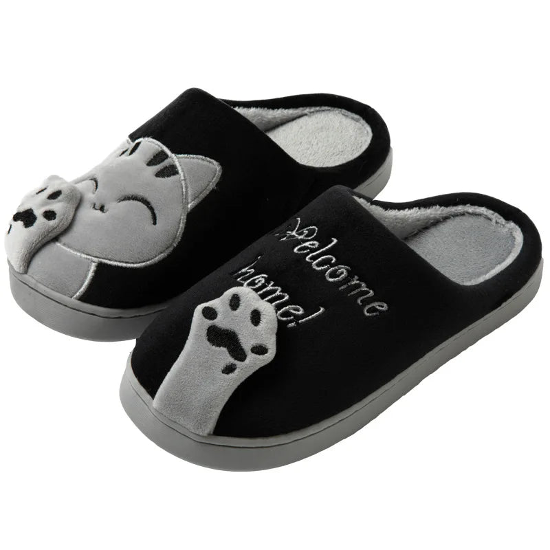 KittyNook Cat Co.’s Happy Pawprints Lucky Cat Slippers feature 3D paws, gray cat faces, and “Welcome home!” text.