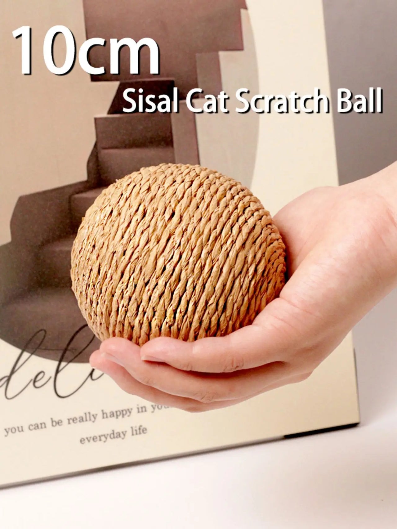 Hand holding KittyNook Cat Co. Premium Sisal Kitten Scratching Ball—10cm eco-friendly cat toy on beige background.