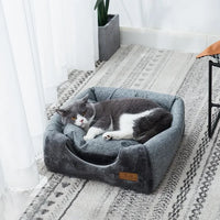 Thumbnail for Gray and white cat lounging in the KittyNook Cat Co. Cozy Triangle Cat Cave Bed on a light-patterned carpet by a window.