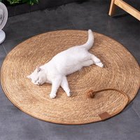 Thumbnail for A white cat relaxes on a KittyNook Cat Co. Natural Rattan Cat Scratcher, enjoying comfort on a gray tile floor.