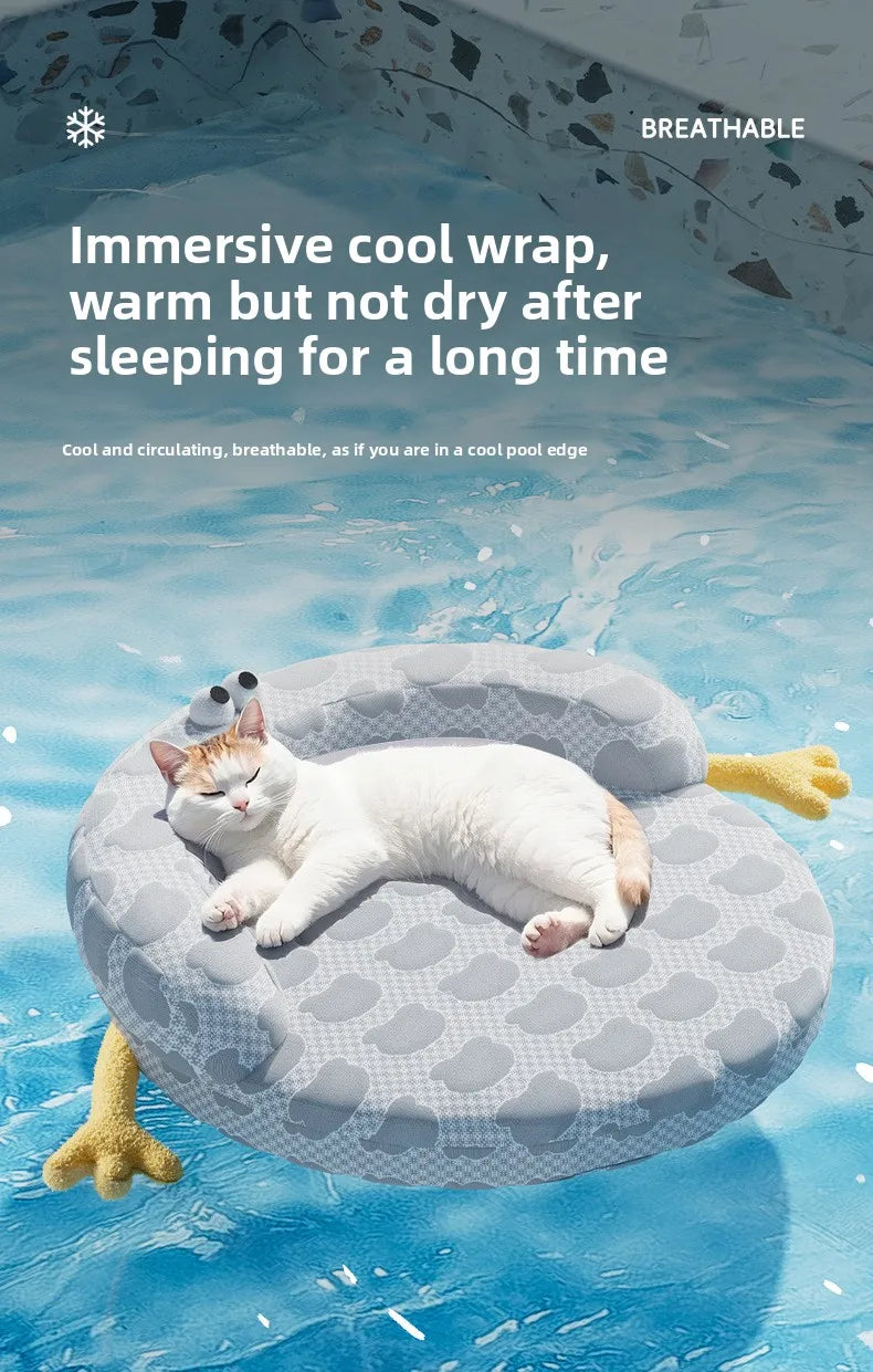 A white cat relaxes on the KittyNook Cat Co. Ice Silk Cat Nest, shaped like a pool float on a blue water background.