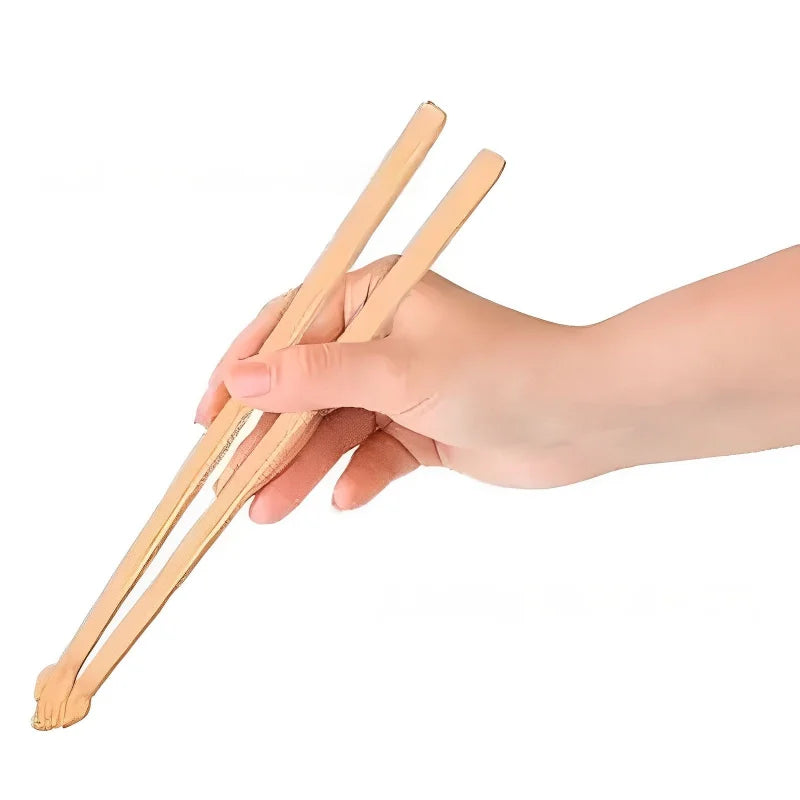 A hand holds KittyNook Cat Co. Little Paws Silicone Training Chopsticks for Kids against a white background.