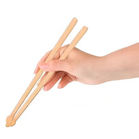 Thumbnail for A hand holds KittyNook Cat Co. Little Paws Silicone Training Chopsticks for Kids against a white background.
