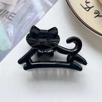 Thumbnail for The KittyNook Cat Co. Cute Cat Hair Claw with bow tie is a chic K-style accessory, shown near a plate and magazine.