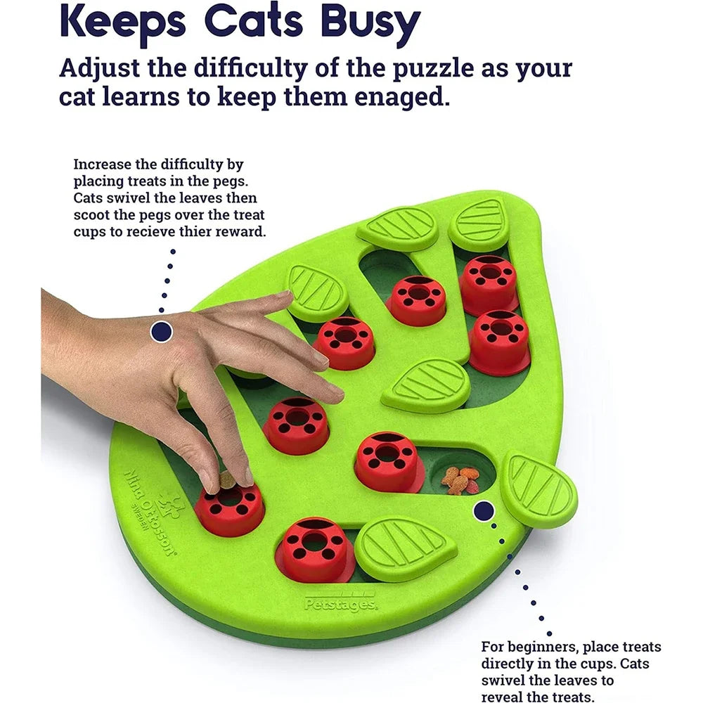 A hand moves KittyNook Cat Co.’s Interactive Cat Treat Puzzle, a leaf-shaped toy with cups and sliders for cat enrichment.