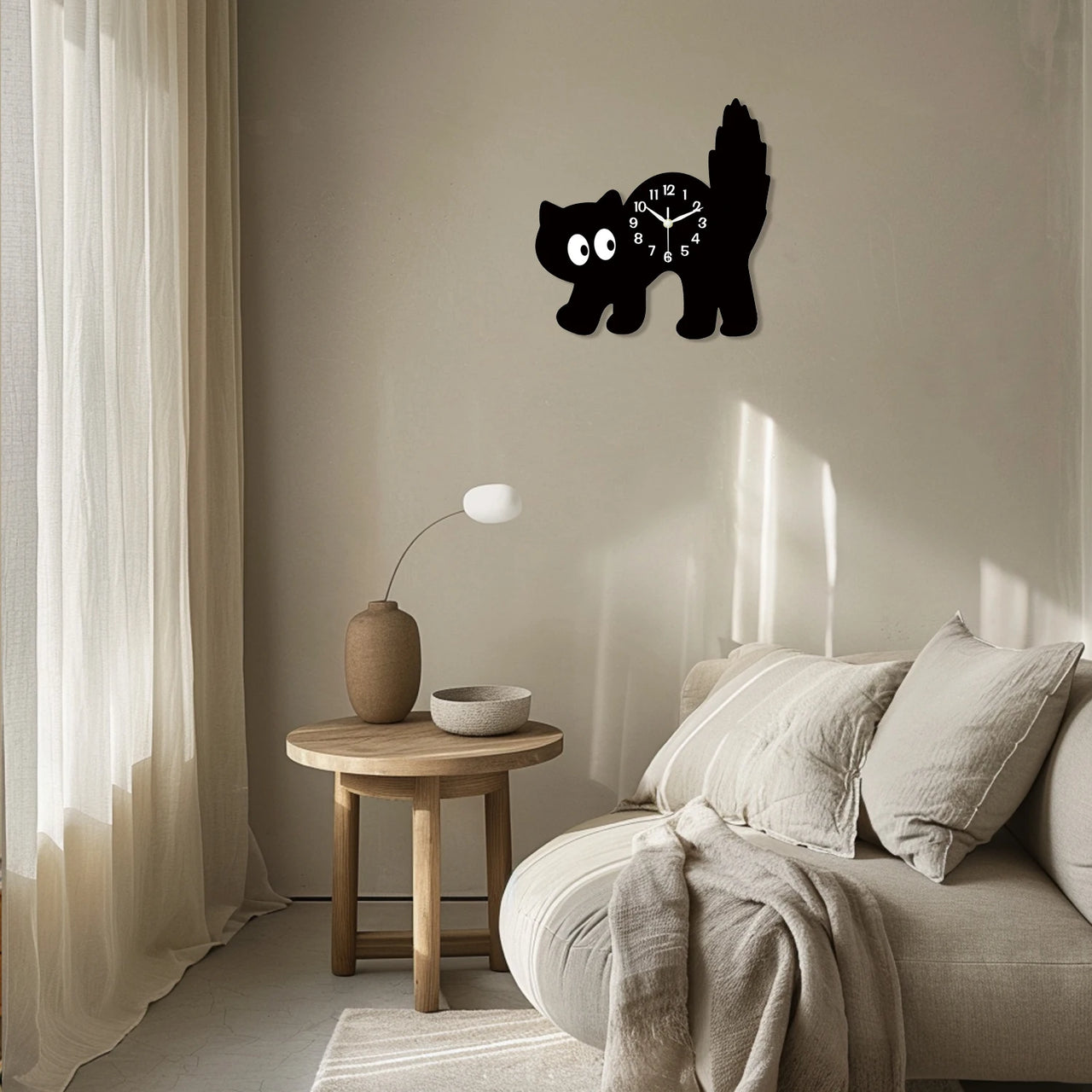 A KittyNook Cat Co. Crystal Porcelain Black Cat Wall Clock hangs above a beige sofa and round wooden table in soft light.