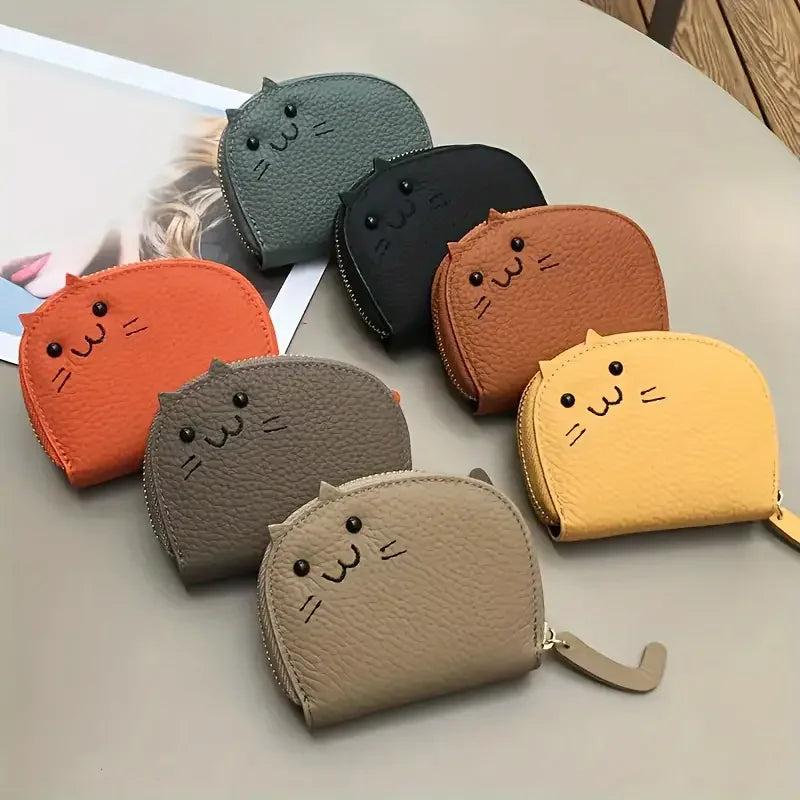 Seven KittyNook Cat Co. Cute Multi-Card Cat Purses are arranged on a table beside a magazine.
