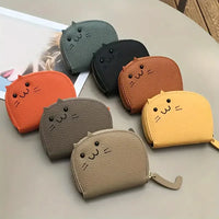 Thumbnail for Seven KittyNook Cat Co. Cute Multi-Card Cat Purses are arranged on a table beside a magazine.