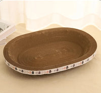 Thumbnail for KittyNook Cat Co. Oval Corrugated Cat Scratching Board with cartoon cats on the edge, shown on a beige surface.