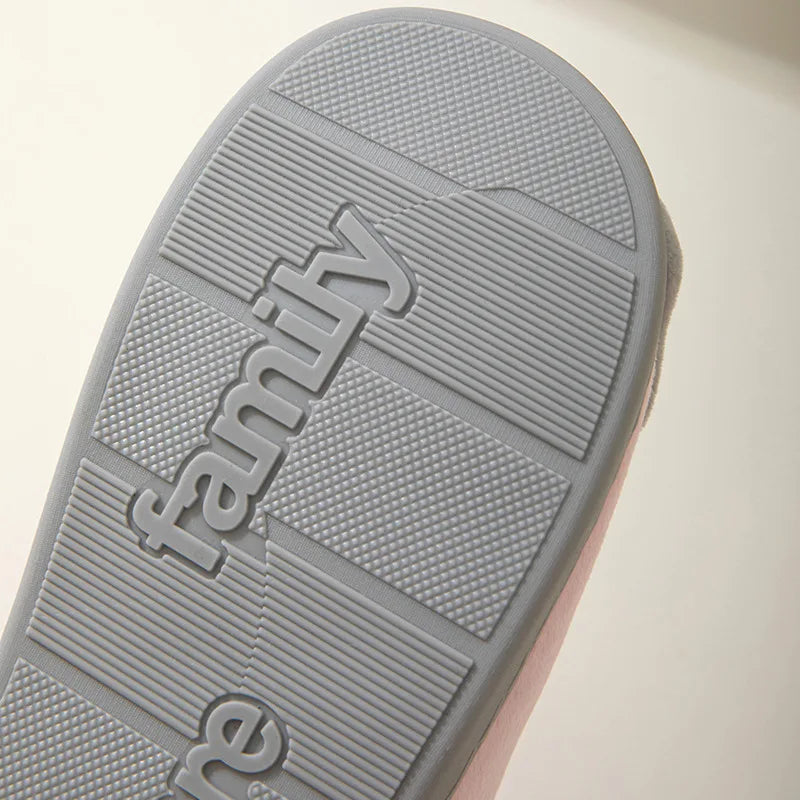 Close-up of a gray Happy Pawprints Lucky Cat Slippers sole by KittyNook Cat Co., "family" embossed on the tread.