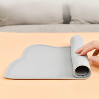 Thumbnail for A hand rolls up the flexible KittyNook Cat Co. Silicone Pet Feeding Bowl on a peach-colored surface.