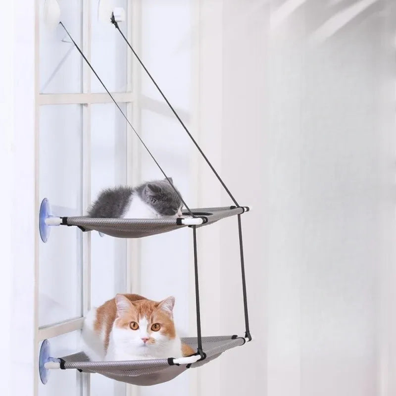 Two cats lounge on the KittyNook Cat Co. Space-Saving Double Hanging Pet Bed, one gray above, orange-white below.