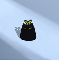 Thumbnail for KittyNook Cat Co. Black Cat Enamel Brooch with yellow eyes and green sprout—ideal jewelry for cat lovers.