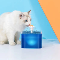 Thumbnail for A white cat drinks from a KittyNook Cat Co. LED Automatic Pet Water Dispenser with Filter, blue-orange backdrop behind.