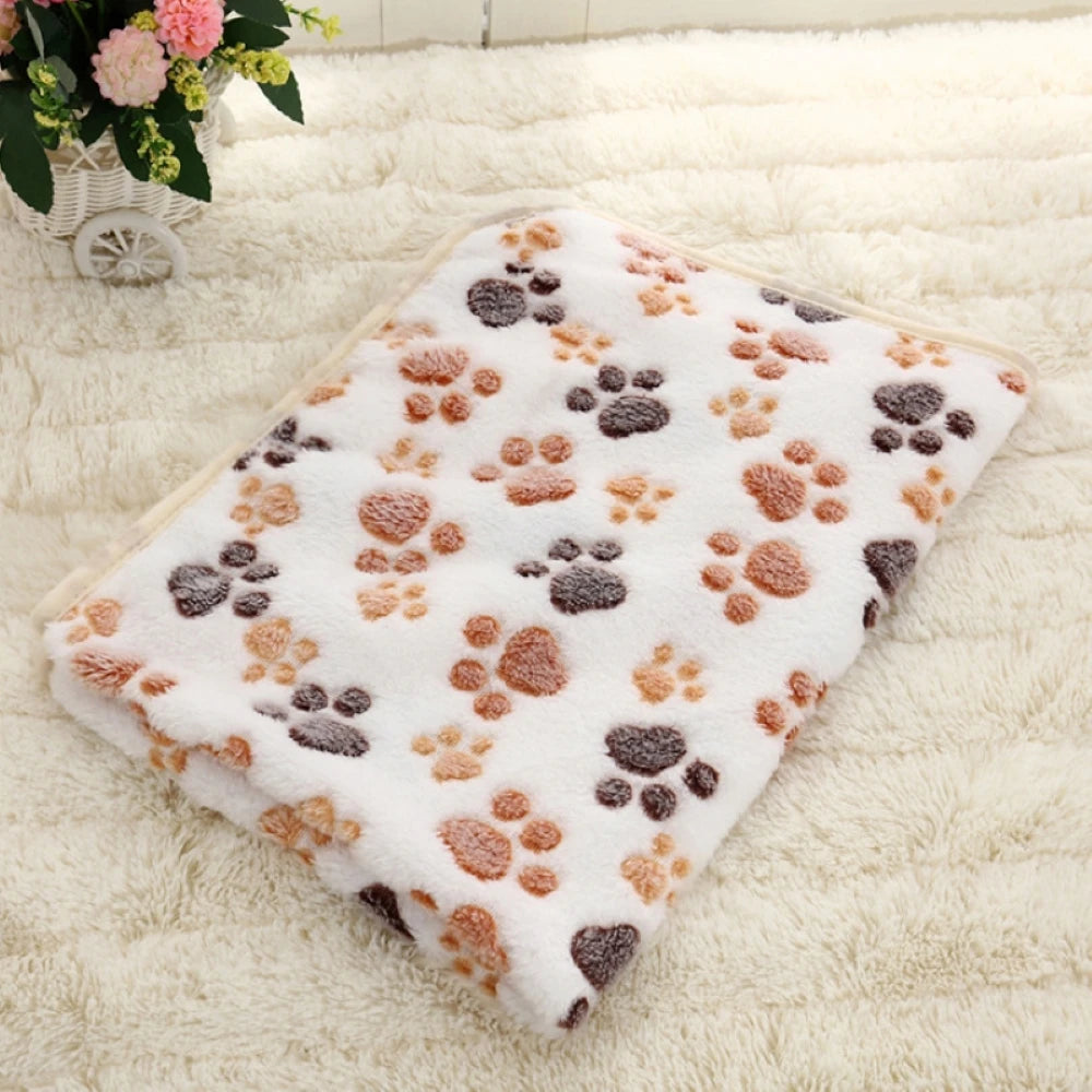 The SnugglePaws Luxe Fleece Pet Blanket by KittyNook Cat Co. rests folded on a fluffy cream-colored rug.