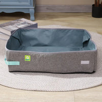 Thumbnail for A gray and blue fabric pet bed sits by KittyNook Cat Co.'s Portable Cat Litter Box on a round beige rug.