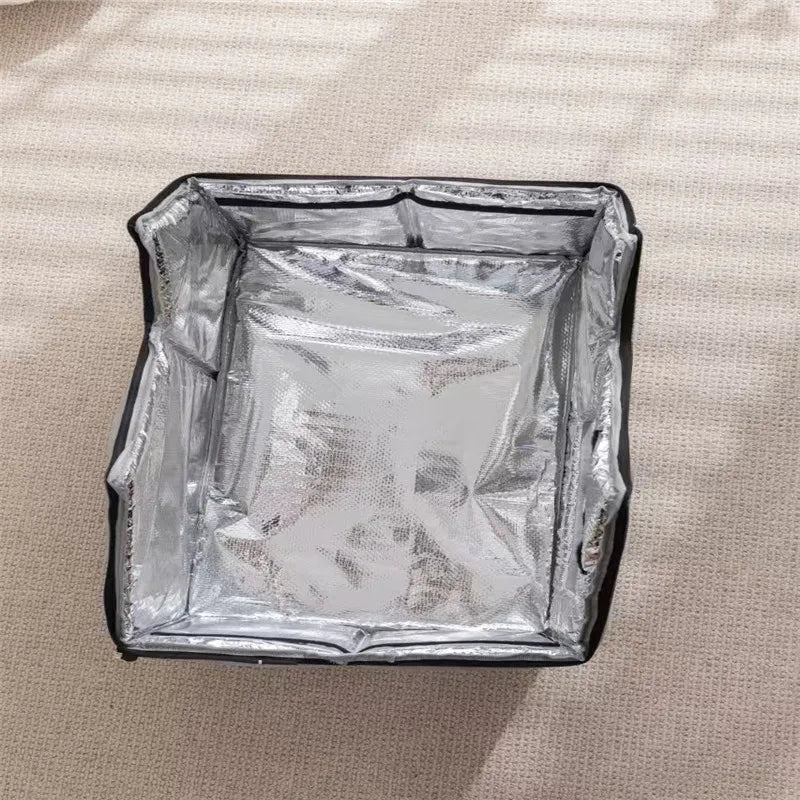 A square silver KittyNook Cat Co. Portable Pet Cooling House sits open on a light carpet in sunlight.