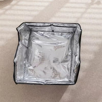 Thumbnail for A square silver KittyNook Cat Co. Portable Pet Cooling House sits open on a light carpet in sunlight.