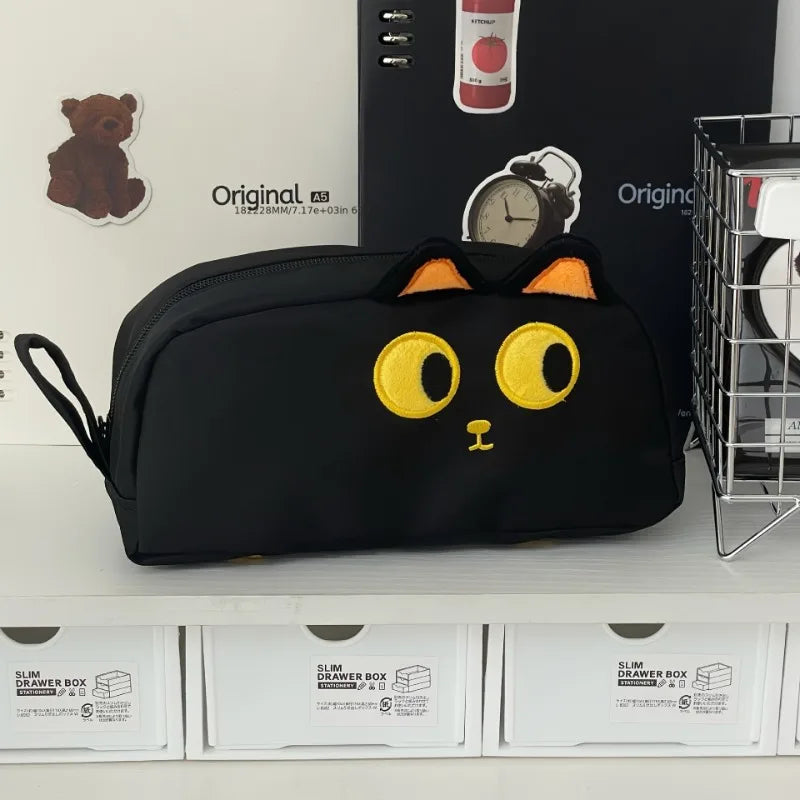 The KittyNook Cat Co. Adorable 3D Cat Pencil Case with yellow accents sits on a shelf with cute stationery.