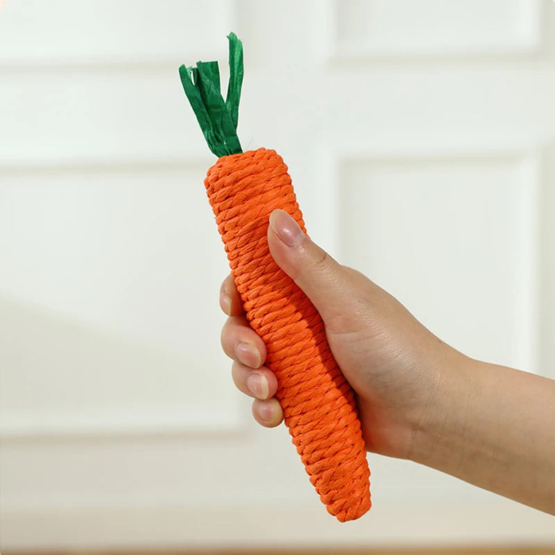A hand holds the KittyNook Cat Co. Bite-Resistant Cat Toy, a carrot-shaped, orange and green toy, against a light background.