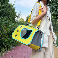 Thumbnail for A person in beige holds the bright yellow Premium Foldable Small Cat Carrying Bag by KittyNook Cat Co. outdoors.