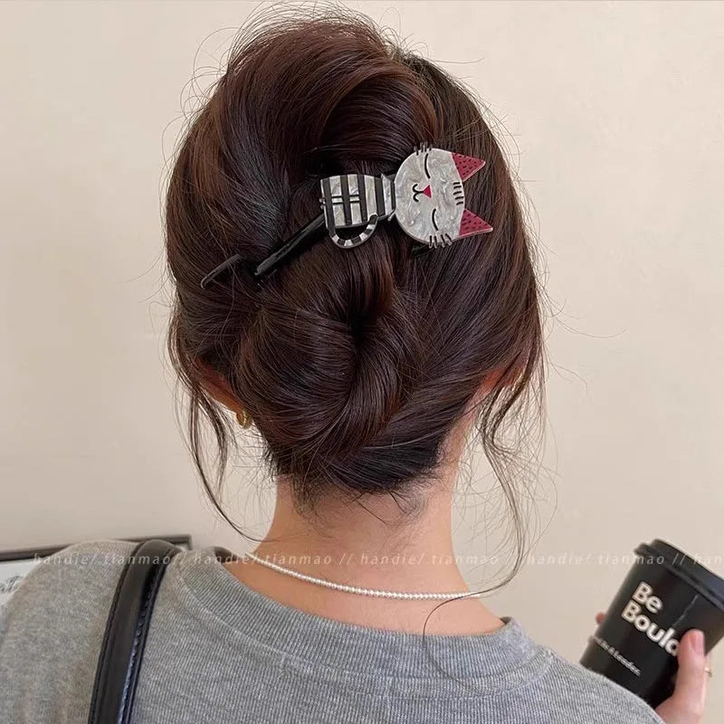 Woman with brown hair in a bun, styled with The Acrylic Cat Hairpin by KittyNook Cat Co., holding a black tumbler.