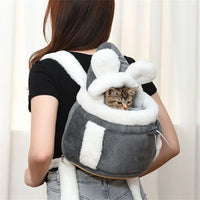 Thumbnail for A woman carries The Stylish Pet Travel Bag by KittyNook Cat Co., a gray and white bunny-shaped pet carrier with a kitten inside.