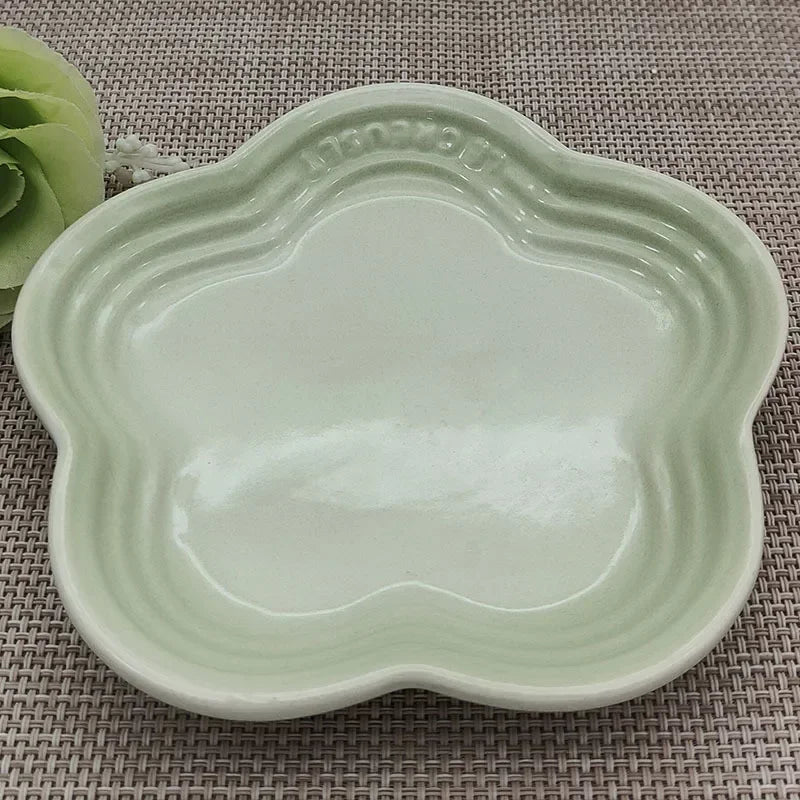 KittyNook Cat Co. Extra Wide Raised Flower Cat Bowl in pale green, shown on a woven beige placemat with decor.